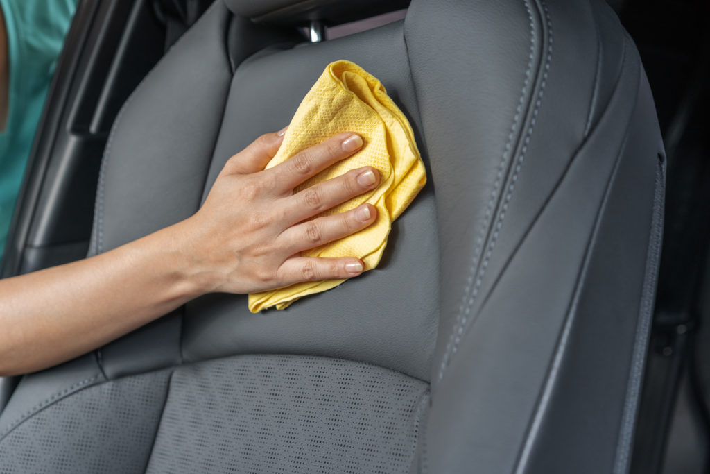 hand with microfiber cloth cleaning leather seat